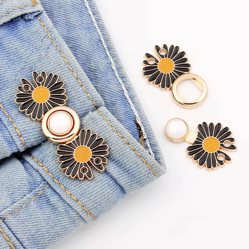 Black daisy waist knots with gold trim, adjustable detachable no-sew pins, shown on denim jeans.